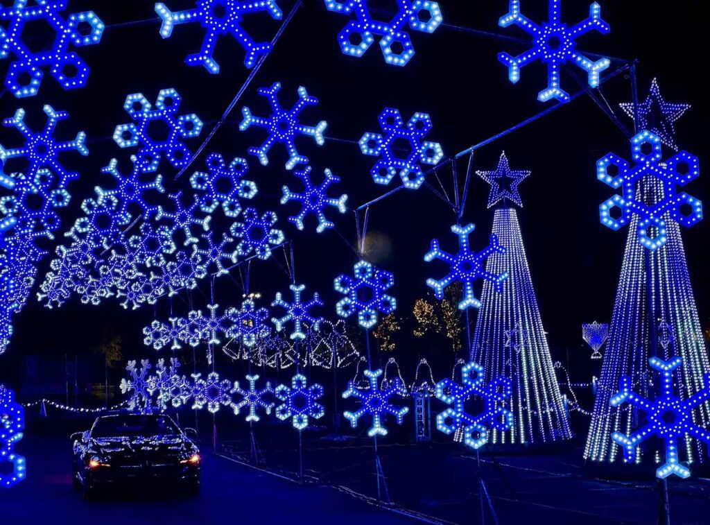 Car going through a tunnel of lights that are shaped light snowflakes.